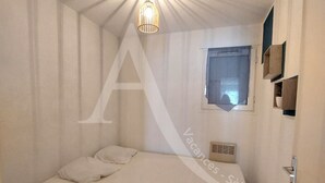 A bedroom with a bed, a window, and a wall-mounted shelf. - T3 avec balcon coeur quartier Corniche (Sète)