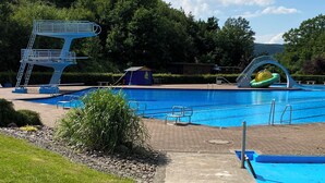 A swimming pool with a diving platform and a water slide.