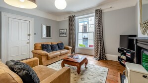 A living room with a sofa, armchair, coffee table, and a fireplace. - 1 Bed in Appledore (oc-s29081) (Appledore)