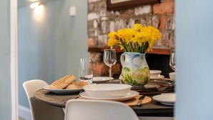 A dining table set with plates, glasses, and a pitcher of yellow flowers. - 1 Bed in Appledore (oc-s29081) (Appledore)