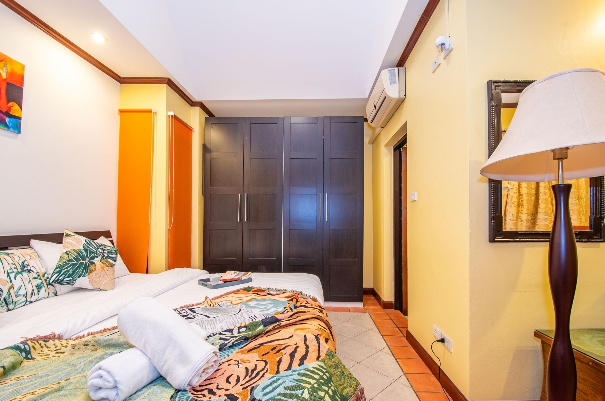 A hotel room with a bed, a wardrobe, a lamp, and a painting on the wall.