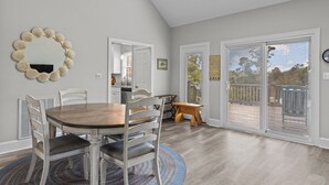 A dining area with a round table, white chairs, a patterned rug, and a large mirror on the wall. - Red Buffalo| Steps to beach and town. (Emerald Isle)