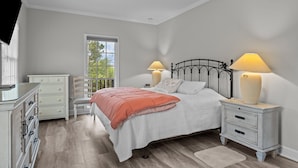 A bedroom with a bed, nightstands, a dresser, and a window with a view. - Red Buffalo| Steps to beach and town. (Emerald Isle)