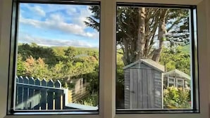 Two windows with views of a fenced yard and a wooden shed. - Delightful Tiny House with stunning views in the Dublin Mountains!

 (Dublin)