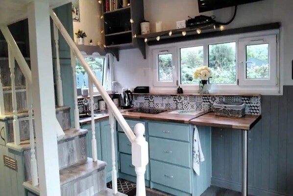 A kitchen with teal cabinets, a wooden countertop, and a window with a view of greenery. - Delightful Tiny House with stunning views in the Dublin Mountains!

 (Dublin)