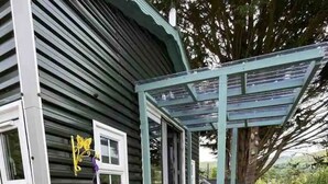 A house with a covered porch, a window with a butterfly decoration, and various potted plants. - Delightful Tiny House with stunning views in the Dublin Mountains!

 (Dublin)