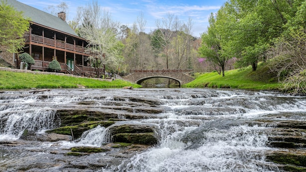 A wooden lodge with a stone bridge over a cascading river. - New! Great Location, Game Room, Hot Tub, King Beds (Sevierville)