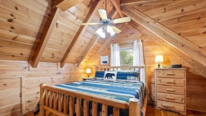 A cozy attic bedroom with a wooden bed, a nightstand, a dresser, and a ceiling fan. - New! Great Location, Game Room, Hot Tub, King Beds (Sevierville)