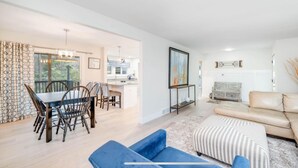 A modern living room with a sofa, ottoman, and dining area with chairs and a table. - Peaceful Creekside Hideaway Near Town (South Haven)