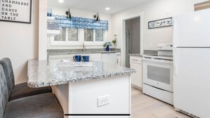 A modern kitchen with granite countertops, white cabinetry, and a built-in oven. - Peaceful Creekside Hideaway Near Town (South Haven)