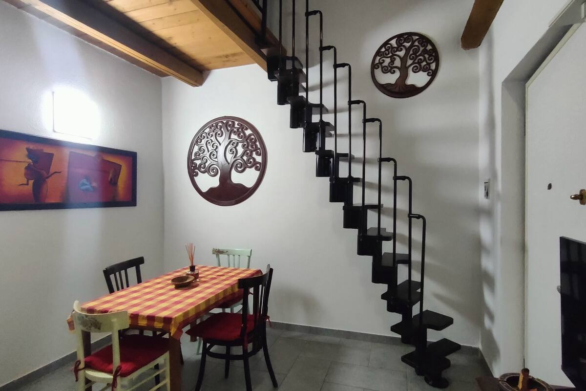 A dining area with a table and chairs, a spiral staircase, and decorative wall art.