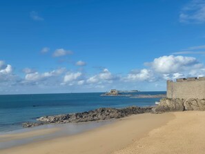 A coastal beach with a rocky shoreline, a sandy beach, and a stone fortification.