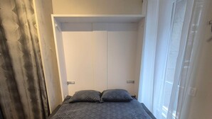 A neatly made bed with a patterned bedspread, two pillows, and two rolled towels.