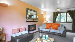 A cozy living room with a fireplace, a sofa, a coffee table with food, and a window with curtains. - Pine Lodge - UK46679 (Bridgnorth and Ironbridge)