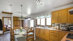 A kitchen with wooden cabinets, a dining table set for four, a refrigerator, and a microwave. - Pine Lodge - UK46679 (Bridgnorth and Ironbridge)