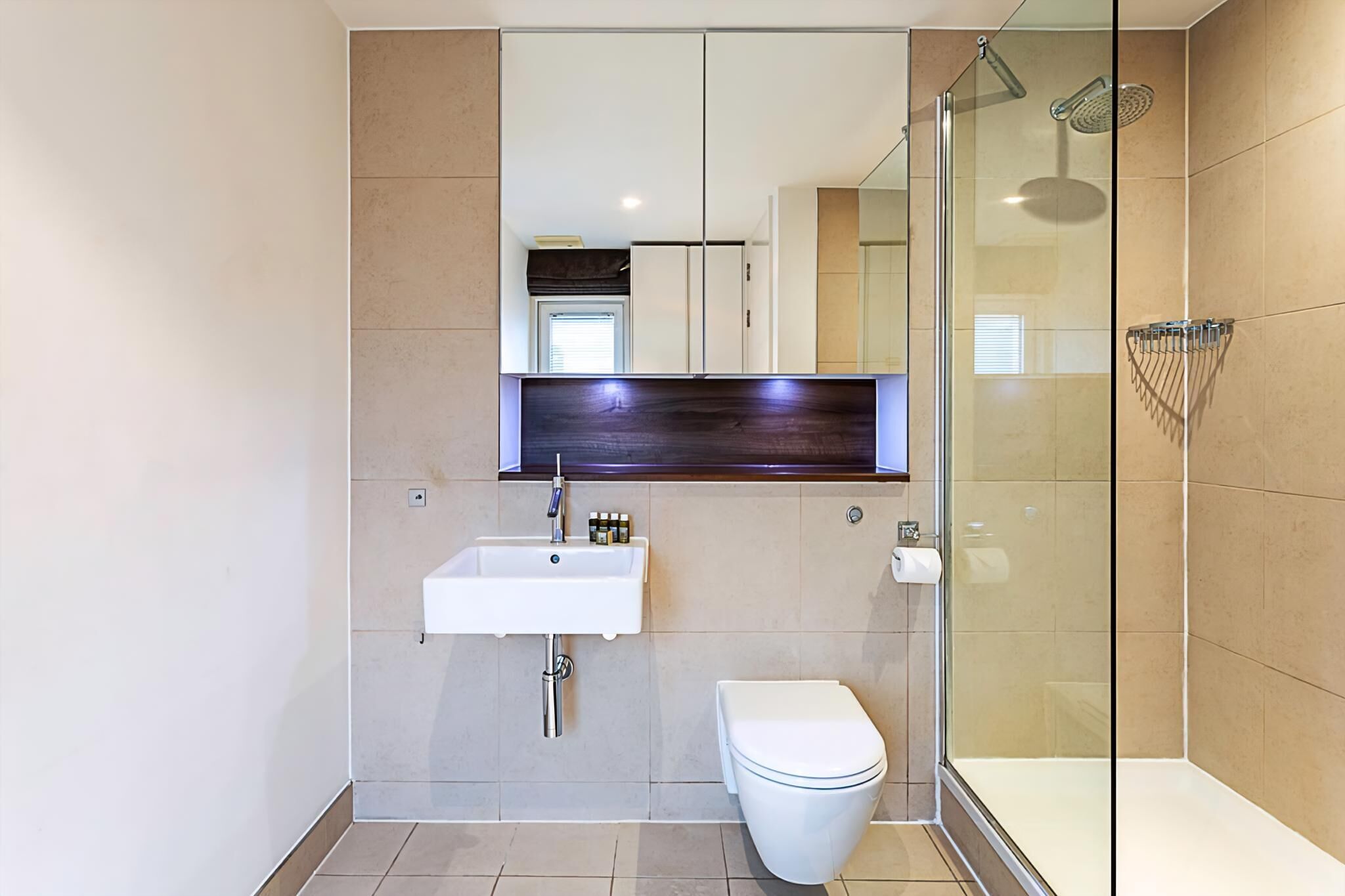 A modern bathroom with a glass shower enclosure, a white sink, and a toilet.