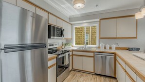 A modern kitchen with stainless steel appliances, wooden cabinets, and a large window providing natural light. - Oceanfront 2rd floor Balcony 2 blocks to Turnaround-Work Remotely (Seaside)