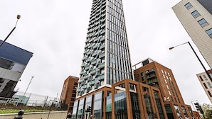 Un edificio moderno de gran altura con una fachada distintiva, rodeado de otras estructuras contemporáneas.