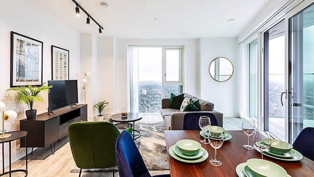 Una sala moderna con comedor, ventanas amplias y vistas a la ciudad.