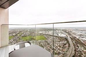Ein Hotelzimmer in einem Hochhaus mit weiter Aussicht auf die Stadt, großen Fenstern und modernem Interieur.