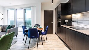 Una cocina moderna con armarios oscuros, una encimera negra y vistas a la ciudad a través de amplios ventanales.