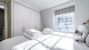 Une chambre avec un grand lit, des rideaux blancs et une fenêtre donnant sur un beau paysage.