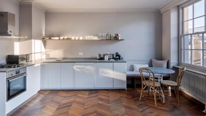 Una cocina moderna con armarios blancos, estufa integrada y una barra desayunadora.