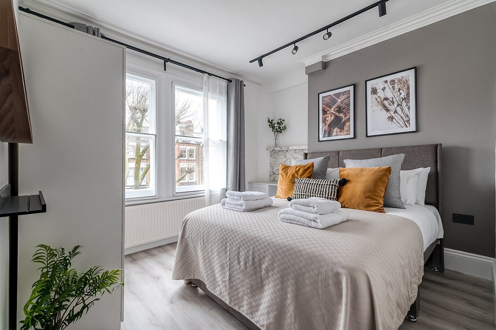 A modern bedroom with a large bed, a view of the city through large windows, and a minimalist decor style.