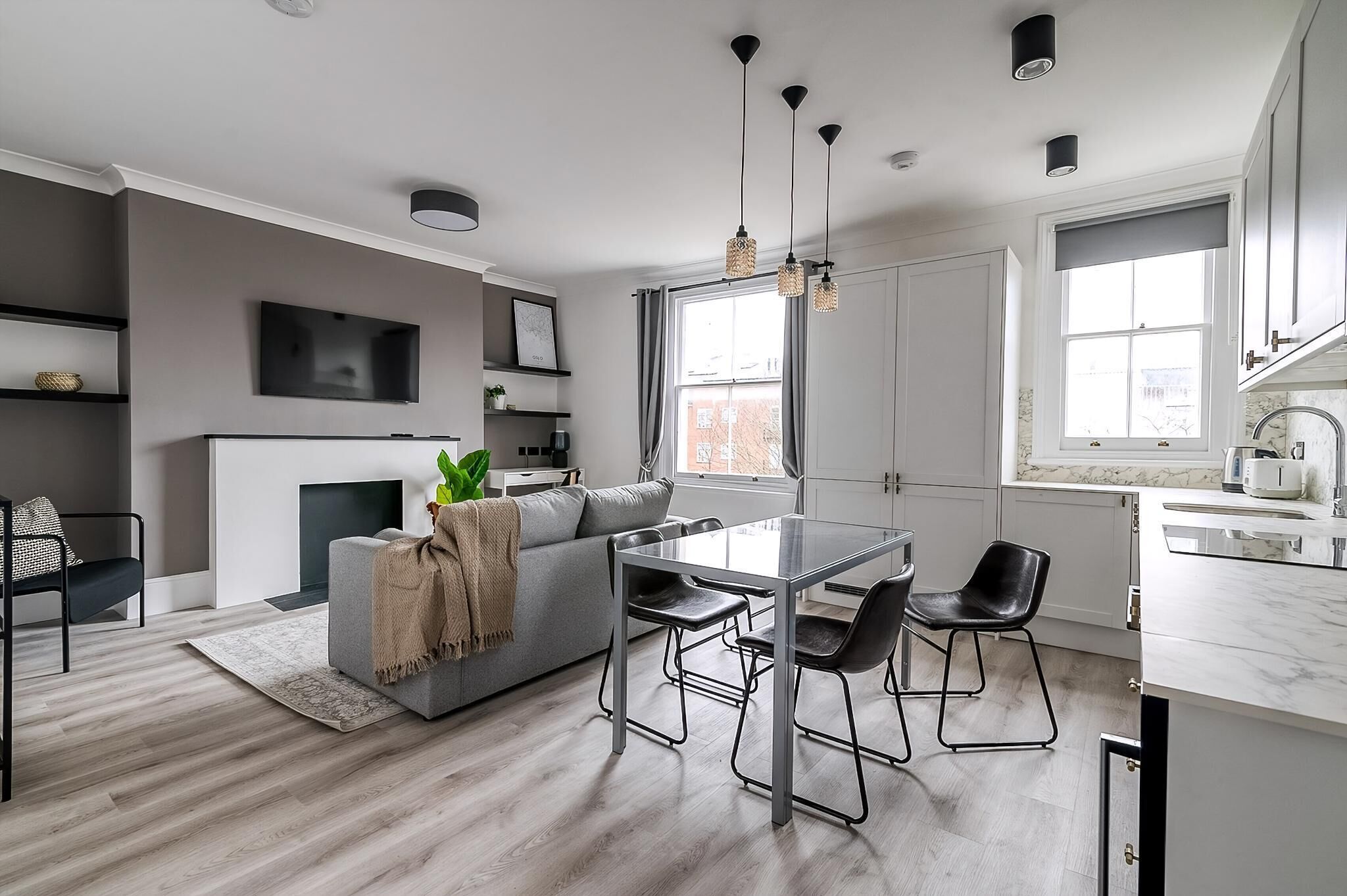 A modern kitchen with a dining area, large windows, and a minimalist design.