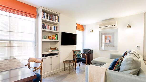 A living room with a sofa, a coffee table, a bookshelf, a flat-screen TV, and a dining table.