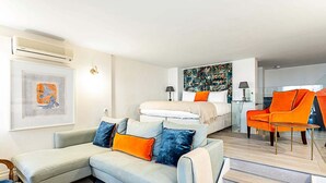 A modern living room with a sofa, a bed, and a bright orange chair.
