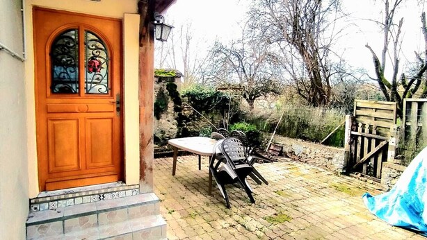 Un edificio rustico con una porta in legno e scale che conducono a un portico piastrellato.