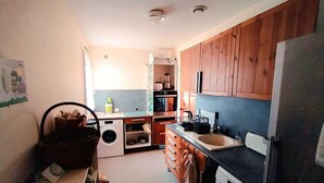 Una cucina compatta con mobili in legno, una lavatrice e un frigorifero.
