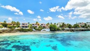Une propriété située en bord de mer, comprenant plusieurs villas, un littoral rocheux et des eaux turquoise cristallines.
