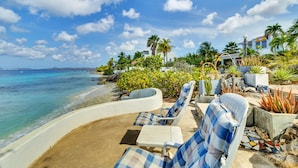 Un complexe hôtelier situé en bord de mer, doté de chaises longues, d’une piscine et offrant une vue sur l’océan.