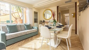 A modern living room with a sofa, dining table, chairs, and a large window with a view of a palm tree. - Penthouse above Trevi Fountain and Panoramic Terrace (Roma)