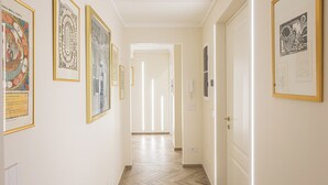 A hallway with framed artworks on the walls, a wooden floor, and a door at the end. - Penthouse above Trevi Fountain and Panoramic Terrace (Roma)