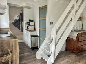 A kitchen with a white staircase, a microwave, and a wooden cabinet. - Quiet vacation home in the dunes of Le Touquet, 2 bedrooms, 5 minutes from downtown (Paris)