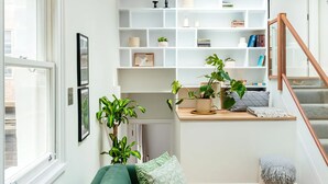 A modern living room with a green sofa, a white bookshelf, and a skylight.
