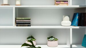 A white bookshelf with books, a candle, and decorative items.