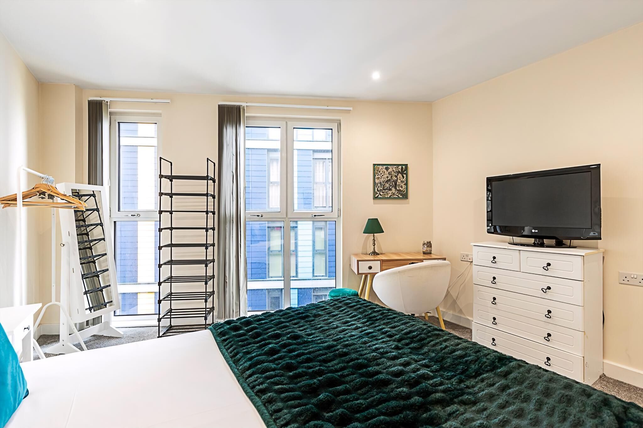 A hotel room with a bed, a desk, a television, and a window with curtains.