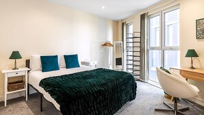 Une chambre d’hôtel comprenant un lit, un bureau, une chaise, une armoire et une fenêtre.