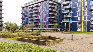 Un immeuble d’appartements moderne doté de nombreux balcons et d’une cour aménagée.