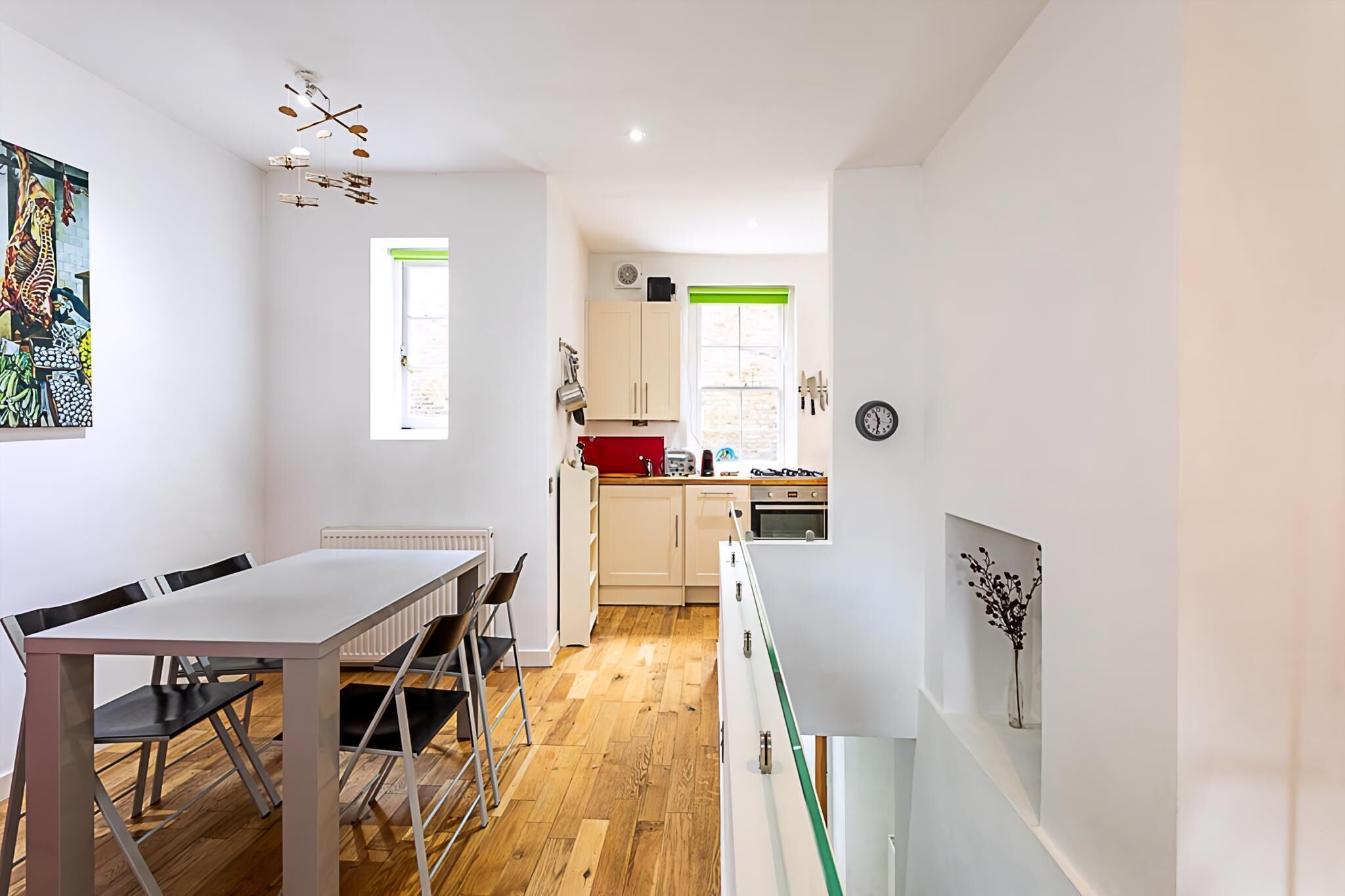 A modern kitchen with a dining area, wooden flooring, and a view of the city.
