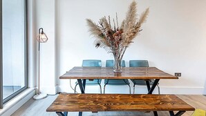 A dining area with a wooden table, chairs, and a vase with dried plants. - Duplex Two-bed Apartment Near Tower Bridge (London)