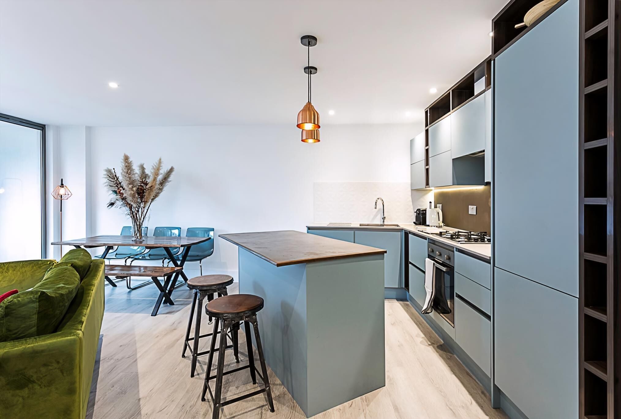 Une cuisine moderne dotée d’un îlot central, de tabourets de bar et d’un coin repas avec des chaises.