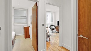 Un pasillo con una cama, un aparador de madera y una silla.