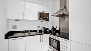 Una cocina moderna con armarios blancos, encimera negra, horno empotrado y campana extractora de acero inoxidable.