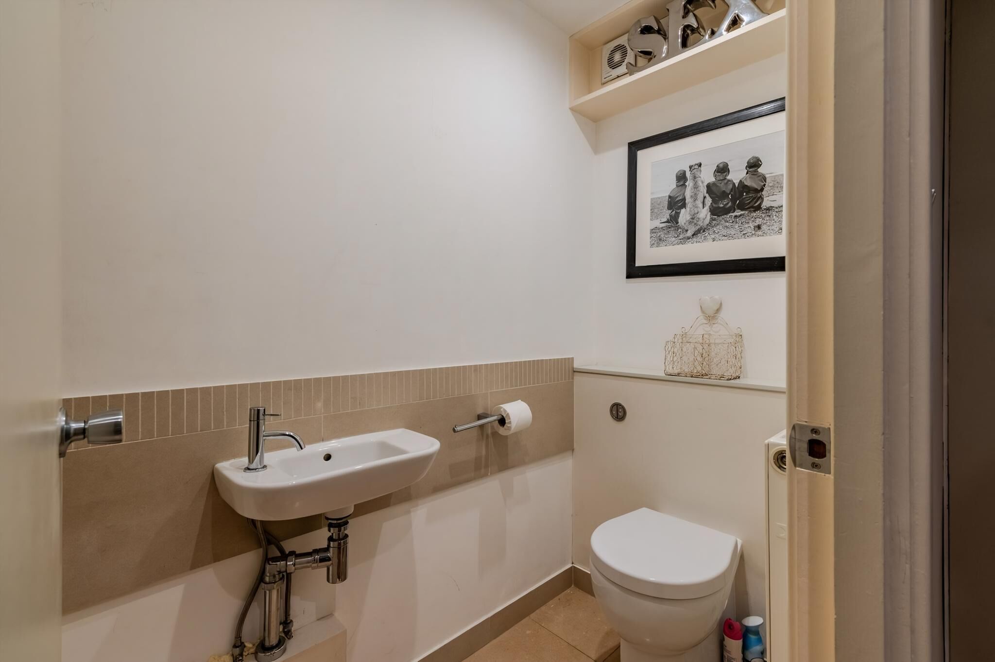 A small bathroom with a white sink, toilet, and a framed photo on the wall.