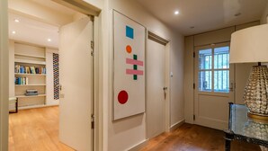 A hallway with a bookshelf, a door with geometric wall art, and a lamp. - Beautiful Three Bedroom House in West London (London)
